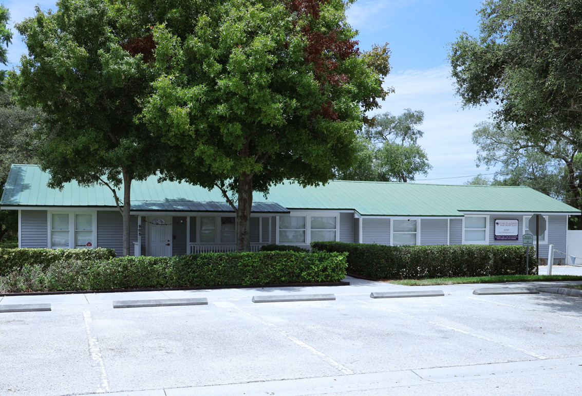 This image is an exterior photograph of a commercial office building located at 905 11th Street, Palm Harbor Florida